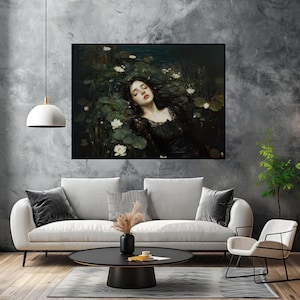 May include: A framed art print showing a woman in a black dress amongst lily pads and white flowers. The artwork has a dark, moody aesthetic, with a focus on the woman's face and the surrounding water. The print is displayed above a white sofa.