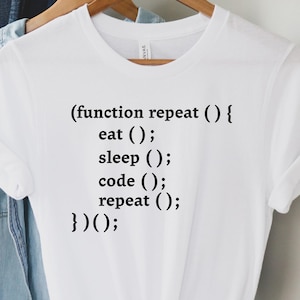 May include: White t-shirt with black text that reads: (function repeat () { eat (); sleep (); code (); repeat (); })();. The shirt is hanging on a wooden hanger with other clothing items.
