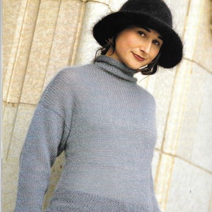 May include: A woman wearing a gray knitted sweater with a black hat. The sweater has a turtleneck and long sleeves.