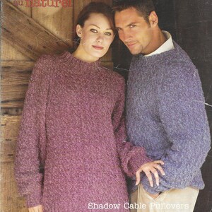 May include: A knitting pattern booklet featuring a couple wearing purple and blue sweaters with a cable knit design. The cover features the text "Patons au naturel" and "Shadow Cable Pullovers His & Her designs, with choice of necklines".