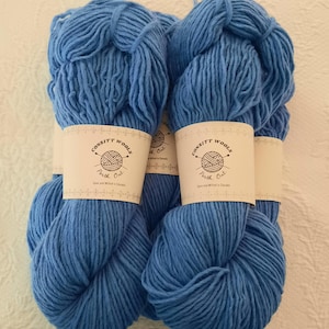 Può includere: Quattro matasse di lana Consitt Wools blu brillante. Ogni matassa ha un'etichetta con la scritta "Consitt Wools, Perth, Ont.". La lana è di colore blu chiaro e sembra morbida, ideale per progetti di maglieria o uncinetto.