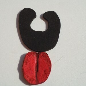 May include: A black foam shape resembling a mouth with a red foam tongue sticking out.
