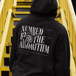 May include: A black hoodie with a white graphic print that says "NUMBED BY THE ALGORITHM" with the words "infinite feed" and "attention span not found - error 155" printed below the graphic.