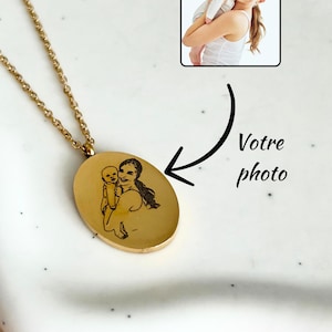 May include: A gold-colored oval pendant necklace with a chain. The pendant features a sketched image of a person holding a baby. The image is next to a small photo of a person holding a baby. The text "Votre photo" is also in the image.