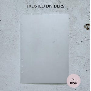 May include: Frosted dividers for an A5 ring binder. The image shows a translucent, rectangular sheet with pre-punched holes along the left edge. The text "FROSTED DIVIDERS" is at the top, and "A5 RING" is in a pink circle at the bottom.