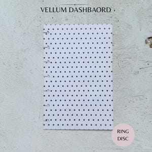 Könnte beinhalten: Ein rechteckiges Vellum-Dashboard mit einem sich wiederholenden Muster aus kleinen schwarzen Punkten auf weißem Hintergrund. Die linke Kante hat eine Reihe von neun gestanzten Schlitzen für ein scheibengebundenes Planersystem. Der Text VELLUM DASHBAORD ist sichtbar.