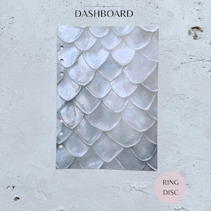 May include: A rectangular planner dashboard featuring a repeating white and iridescent gray fish scale pattern. The left edge contains six circular punched holes for ring binding. The word DASHBOARD is printed at the top, and RING DISC at the bottom.
