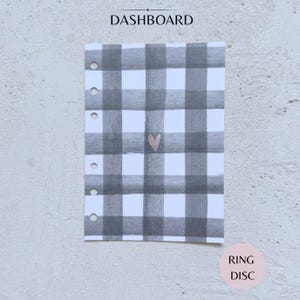 May include: A rectangular planner dashboard featuring a grey and white watercolour plaid pattern with a small metallic heart in the centre. The left side has six circular punch holes for ring binding. The text DASHBOARD and RING DISC are visible.