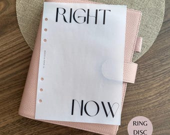 Puede incluir: Una agenda de cuero texturizado rosa claro con cierre de broche y una hoja de papel vegetal translúcido encima. La hoja presenta el texto negro RIGHT en la parte superior y NOW en la inferior, con una fila vertical de seis agujeros a la izquierda.