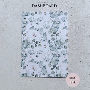 May include: A rectangular planner dashboard featuring a white background with a repeating pattern of sage green eucalyptus leaves and small pink floral accents. The left edge has six circular punched holes for binder rings.