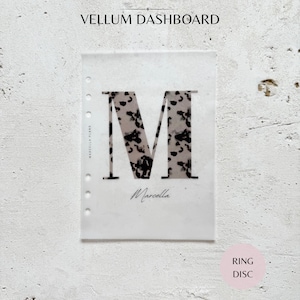 May include: A translucent vellum dashboard insert featuring a large letter M with a black and white animal print pattern. The text "VELLUM DASHBOARD" appears at the top, "MARCELLA PLANS" vertically on the left, and "Marcella" in script below the letter.