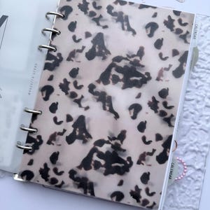 May include: A white ceramic mug with a black handle and the text "But First, Coffee" in a black, handwritten-style font. The mug is on a white surface.