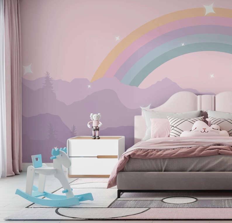 Pu&ograve; includere: Una cameretta con un murale arcobaleno pastello, un cavallo a dondolo bianco e blu e un letto con biancheria da letto rosa. Un piccolo comodino bianco contiene una statuina. La stanza ha un'atmosfera morbida e accogliente.
