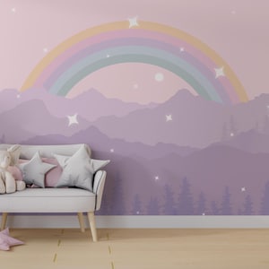 Könnte beinhalten: Eine skurrile Szene im Kinderzimmer mit einem pastellfarbenen Regenbogen-Wandbild über einem weißen Loveseat mit sternförmigen Kissen und einem Stoffelefanten. Ein rosa sternförmiges Kissen liegt auf dem Boden. Die Wandkunst zeigt Berge, Bäume und Sterne.