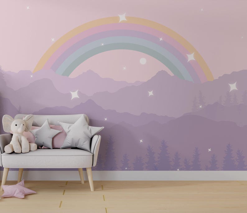 Pu&ograve; includere: Una scena di asilo nido stravagante con un murale arcobaleno pastello sopra un divano bianco con cuscini a forma di stella e un elefante di peluche. Un cuscino a forma di stella rosa poggia sul pavimento. L'arte murale raffigura montagne, alberi e stelle.