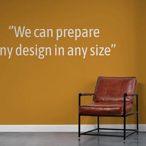 Pu&ograve; includere: Una poltrona in pelle marrone con struttura in metallo nero &egrave; posizionata contro un muro color senape. Il muro presenta il testo "We can prepare any design in any size" in bianco. Un pannello in legno scuro &egrave; a destra.