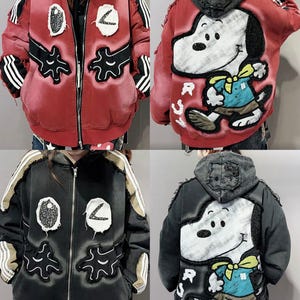 Könnte beinhalten: Rote und schwarze Jacke mit Reißverschluss und weißen Streifen an den Ärmeln. Die Jacke hat Aufnäher mit abstrakten Designs und eine große Snoopy-Grafik auf dem Rücken. Die Jacke hat einen Used-Look.