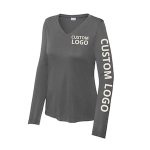 May include: A dark gray long-sleeve V-neck shirt. The text "CUSTOM LOGO" is printed in white on the left chest and down the left sleeve. The shirt is made of a soft, lightweight material.