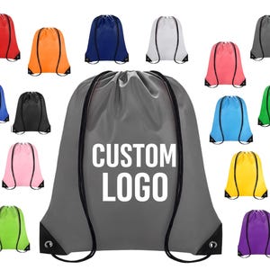 May include: A collection of drawstring backpacks in various colors, including red, orange, blue, white, pink, gray, blue, black, green, yellow, and purple. The central bag is gray with the text "CUSTOM LOGO".