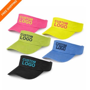 May include: A selection of visors in pink, yellow, green, blue, and black. Each visor displays the text "CUSTOM LOGO". The visors are made of a soft material, suitable for outdoor activities. Ideal for sports or sun protection.