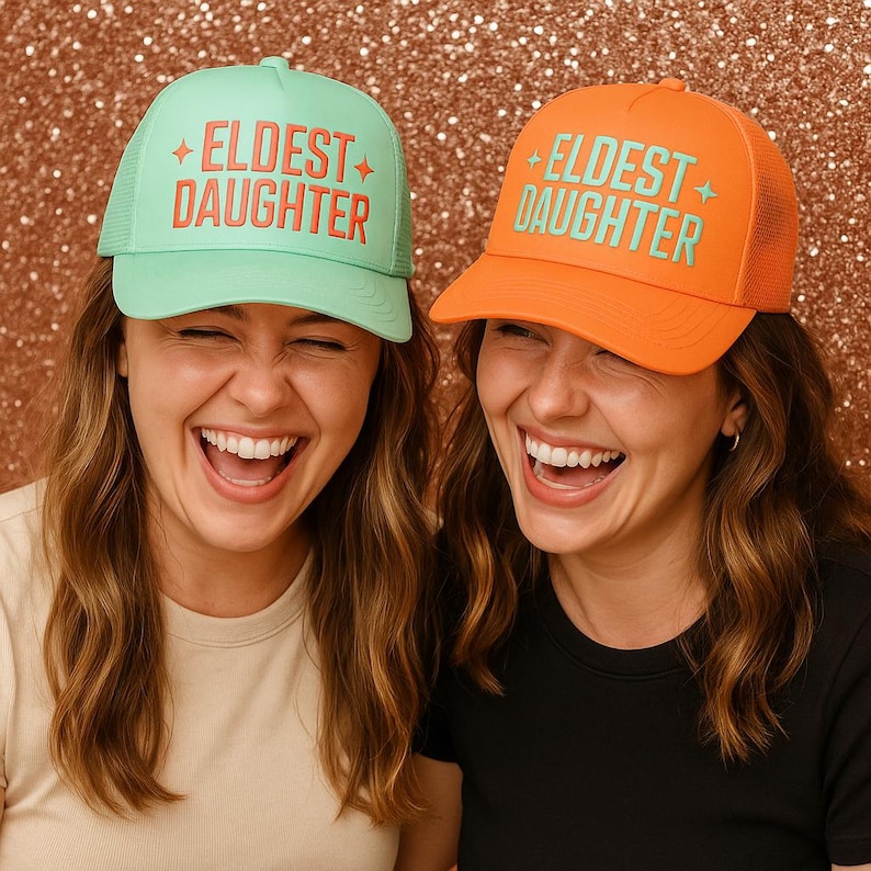 Two women laughing and wearing colorful eldest daughter trucker hats, designed as a fun family keepsake and thoughtful gift for daughters, perfect for birthdays or sibling celebrations.