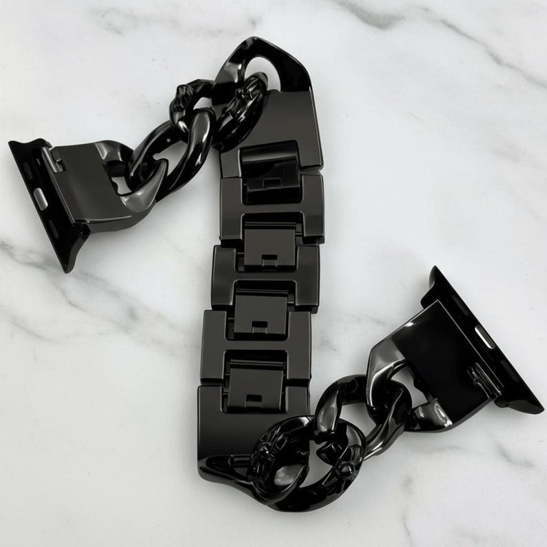以下が含まれることがあります： 黒いチェーンリンクデザインの時計バンド。 バンドは光沢のある光沢のある素材でできており、チェーンで接続された一連の長方形のリンクが特徴です。 バンドはスマートウォッチに取り付けるように設計されています。