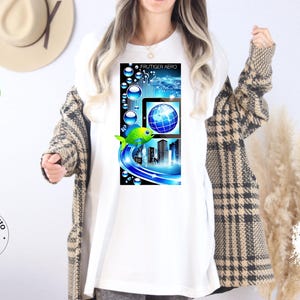 May include: White t-shirt featuring a colorful graphic design. The design includes a fish, a globe, and a cityscape, with the text "FRUTIGER AERO" at the top. The shirt is part of the Family Fashio Store collection.