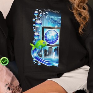 May include: Black hoodie featuring a colorful graphic with the text "FRUTIGER AERO." The design includes a blue and green fish, a tablet with a globe, and city skyline elements. The hoodie has a relaxed fit.
