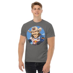 May include: A charcoal grey t-shirt with a circular graphic of a cartoon man wearing a cowboy hat and racing gear. The man is holding a red bull can and the text "Red Bull" is visible on the can.