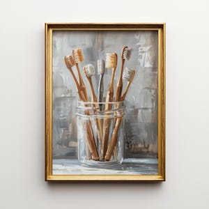 Pode incluir: Pintura emoldurada que retrata um frasco de vidro transparente cheio de várias escovas de dentes. As escovas de dentes têm cabos de madeira castanho claro e cerdas brancas. Uma escova de dentes tem um cabo prateado. O fundo é um design abstrato cinza e branco.