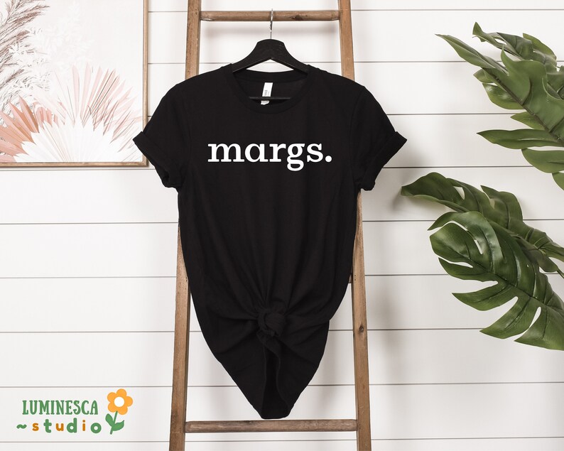 Pu&ograve; includere: Maglietta nera con la parola "margs." stampata in bianco sul davanti.