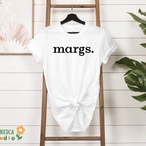 Pu&ograve; includere: Maglietta bianca con la parola "margs." stampata in nero sul davanti.