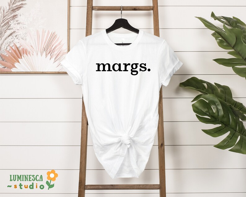 Pu&ograve; includere: Maglietta bianca con la parola "margs." stampata in nero sul davanti.