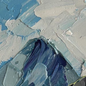 May include: Close-up of an abstract oil painting with thick brushstrokes. The artwork features a palette of blues, whites, and hints of purple, creating a textured, mountainous landscape effect. The paint is applied in a heavy impasto style.