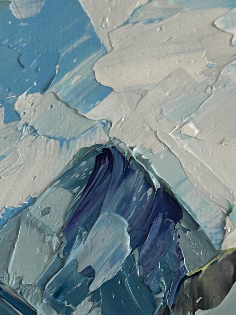 May include: Close-up of an abstract oil painting with thick brushstrokes. The artwork features a palette of blues, whites, and hints of purple, creating a textured, mountainous landscape effect. The paint is applied in a heavy impasto style.
