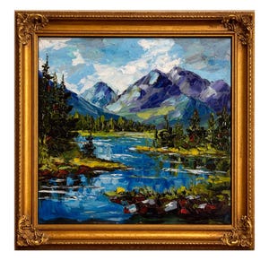 May include: Oil painting of a mountain landscape with a lake, framed in a gold ornate frame. The artwork features a blue lake, green trees, and purple mountains under a blue sky with white clouds.