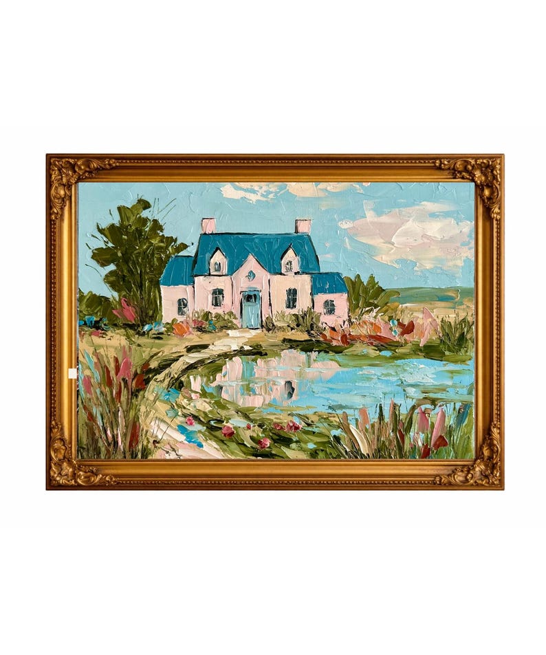 May include: An oil painting in a gold ornate frame depicting a light pink house with a blue roof situated beside a pond. The scene features thick, textured brushstrokes, green foliage, and a light blue sky with soft white clouds reflected in the water.