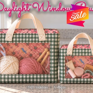 May include: Two rectangular quilted pouches with green and white gingham borders and a pink floral interior. Each features a clear vinyl window, cream-colored fabric handles, and a zipper. The text reads Daylight Window Pouch and Super Sale.