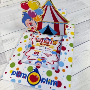 Puede incluir: Una colorida invitación de cumpleaños con una carpa de circo emergente y un payaso de dibujos animados sosteniendo globos. La invitación tiene un fondo blanco con lunares y el texto "Plim Plim". La invitación es para el 1er cumpleaños de Ezequiel.
