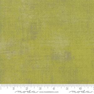 May include: A close-up of a green fabric with a subtle textured pattern. The fabric has a slightly faded look, giving it a vintage feel. The fabric is measured in inches with a ruler at the bottom of the image.