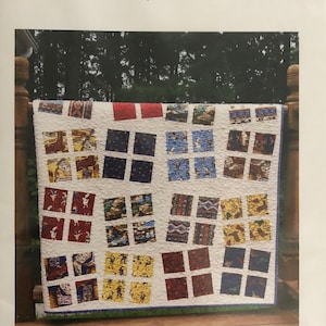 May include: A patchwork quilt with a white background and squares of various colors and patterns, including red, blue, yellow, and brown. The quilt is hanging on a wooden railing with a green background. The text "Dancing Patchwork Quilt" is at the top of the image and "Carlene Westberg Designs #cfw-006" is at the bottom.