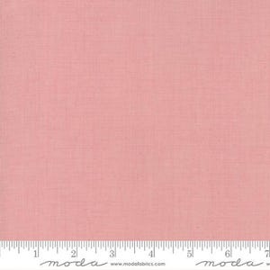May include: A plain, pale pink fabric with a fine woven texture. The material is uniformly coloured and likely cotton or a similar weave. A ruler with inch markings is visible along the bottom edge.