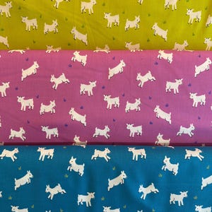 May include: Three fabric swatches with a repeating pattern of white goats running on a colored background. The top swatch is yellow, the middle swatch is pink, and the bottom swatch is blue.