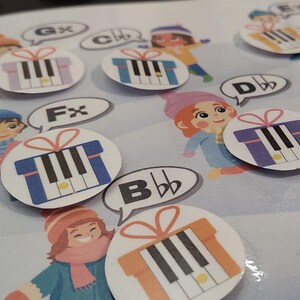 May include: A children's educational game featuring illustrations of cartoon children and musical notes. The game includes circular gift-shaped cards with piano keys and musical notations like "G#" and "C#". The background is a light blue, snowy scene.