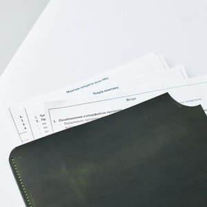 May include: A close-up of a black leather-bound notebook with a yellow stitch along the edge. The notebook is partially covering a white sheet of paper with the text "Монтаж інтерв'ю (міні МК)" and "Теорія монтажу" in black text. The text "Вступ" is also visible in black text.