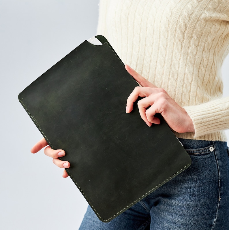 May include: A dark green leather laptop sleeve with a stitched edge.