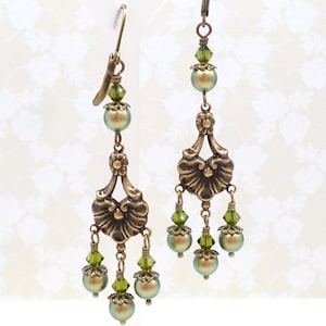 shimmery green pearls are paired with olive crystals in these Victorian reproduction chandelier earrings, handmade by me.  The chandelier connectors have a floral motif in antique brass, and the ear wires are antique brass in a lever back style.
