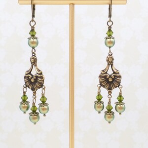 shimmery green pearls are paired with olive crystals in these Victorian reproduction chandelier earrings, handmade by me.  The chandelier connectors have a floral motif in antique brass, and the ear wires are antique brass in a lever back style.