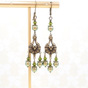 shimmery green pearls are paired with olive crystals in these Victorian reproduction chandelier earrings, handmade by me.  The chandelier connectors have a floral motif in antique brass, and the ear wires are antique brass in a lever back style.