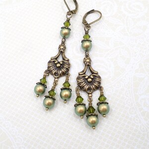 shimmery green pearls are paired with olive crystals in these Victorian reproduction chandelier earrings, handmade by me.  The chandelier connectors have a floral motif in antique brass, and the ear wires are antique brass in a lever back style.